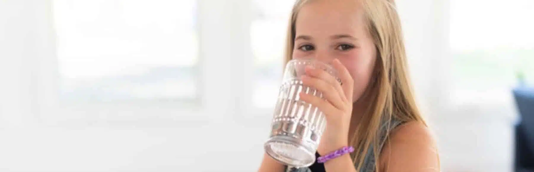 little girl drinking from a glass of water
