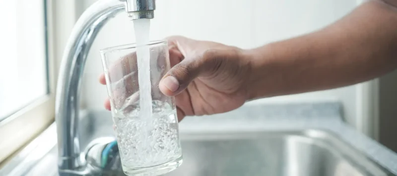 refilling glass of water from a faucet tap.
