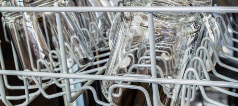 closeup of glass cups sitting upside down in a dishwasher